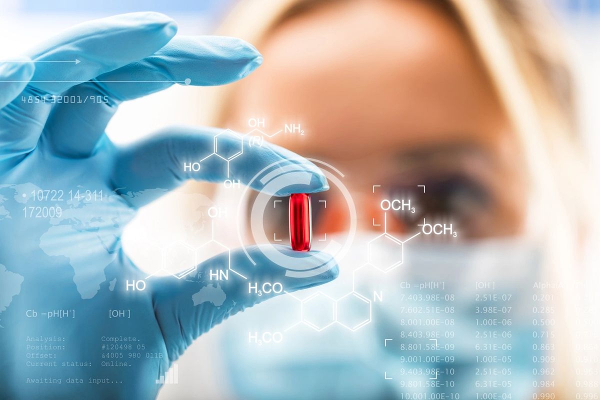 Scientist holding a red capsule with chemical formulas over it
